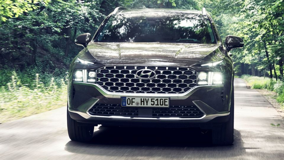 Nové sedmimístné SUV Hyundai Santa Fe Plug-in Hybrid jede po silnici lesem.