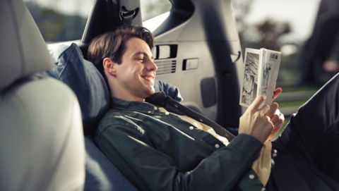 Muž, relaxující v prostorné zadní části zcela nového kompaktního SUV Hyundai TUCSON Plug-in Hybrid.