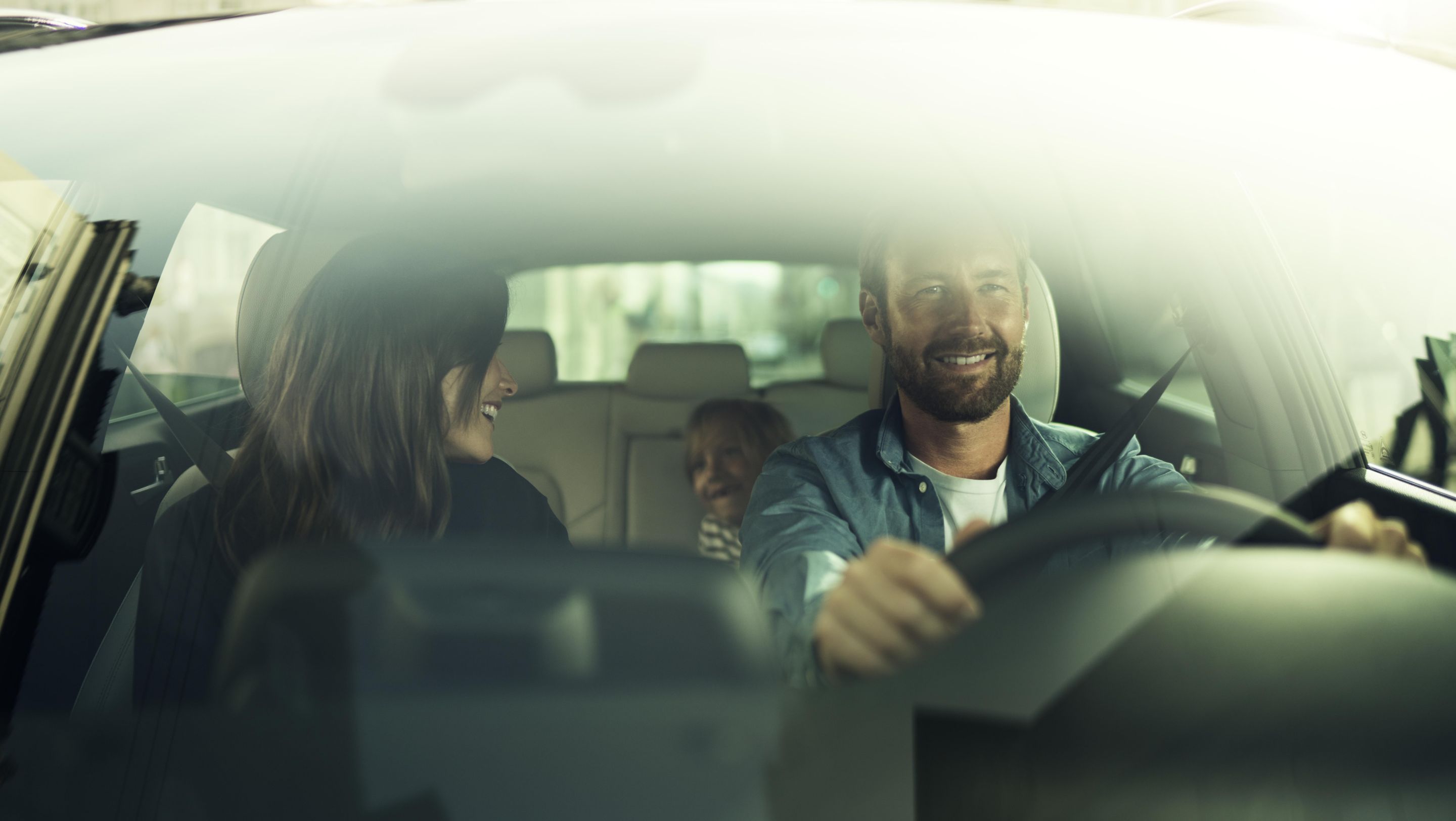 Při pohledu do vozu Hyundai přes čelní sklo je vidět spokojenou rodinu.
