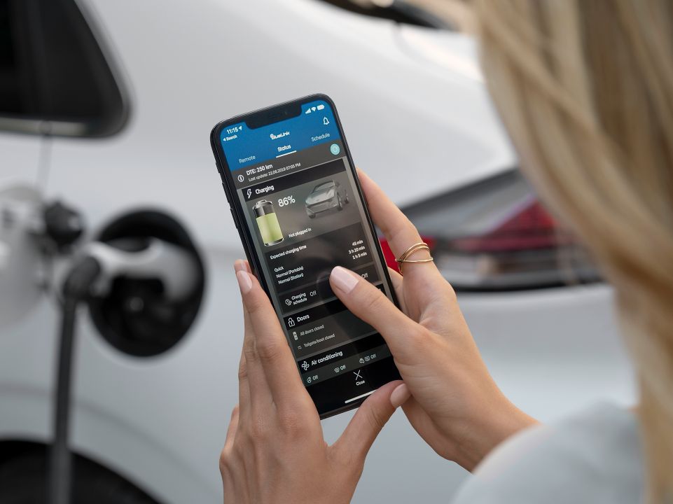 Žena, která během nabíjení auta kontroluje na svém telefonu stav svého vozu Hyundai IONIQ.
